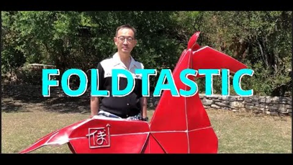 Kyle Fu with a large red origami sculpture.